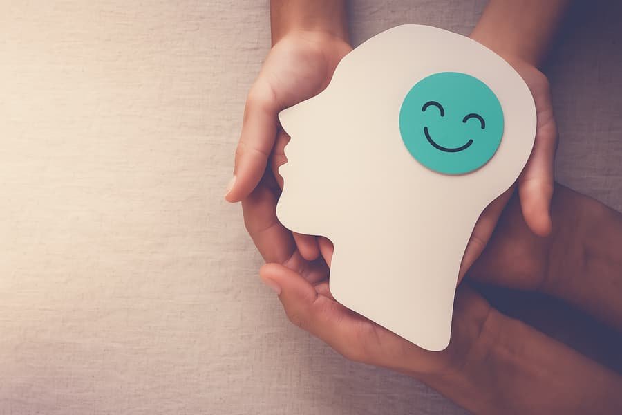 Psychology of Spending: Hands holding a brain cutout with a smiling face symbolizing positive emotions and dopamine release during spending.