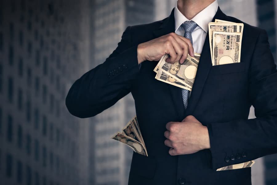 trading-courses-scam A man in a suit stuffing cash into his jacket symbolizing the truth behind trading courses and the question are trading courses worth it