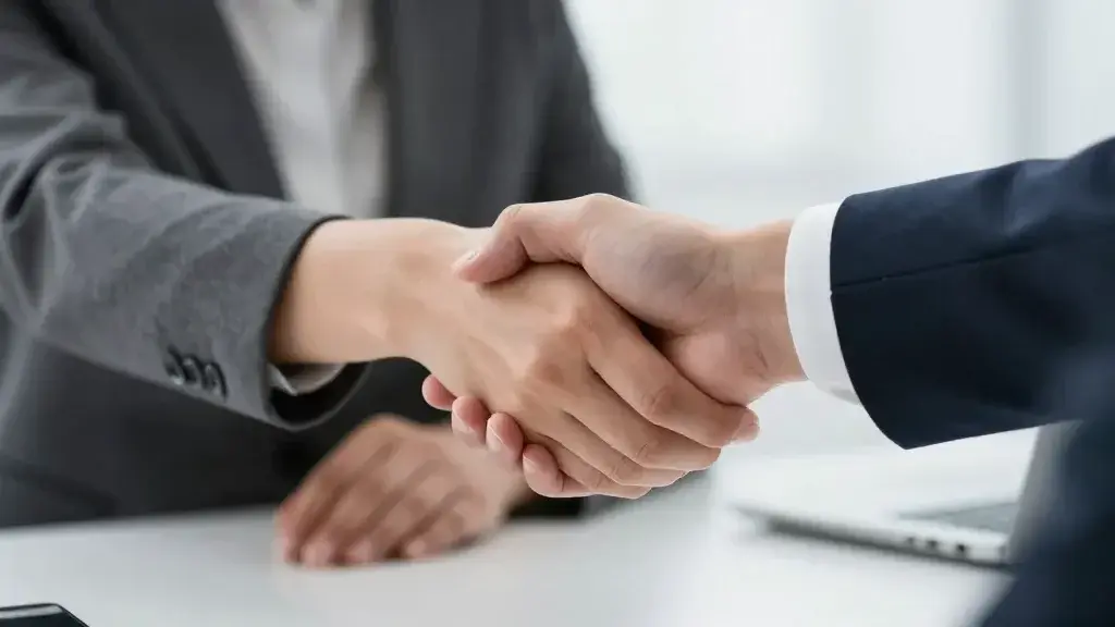 Professional businesswoman shaking hands across desk, closeup shot